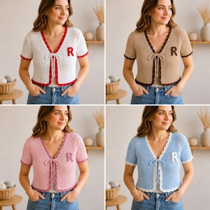 May include: A short-sleeved crochet cardigan featuring a front tie closure and a letter R patch on the chest. The garment is available in four color variations: white with red trim, tan with brown trim, pink with dark pink trim, and blue with white trim.