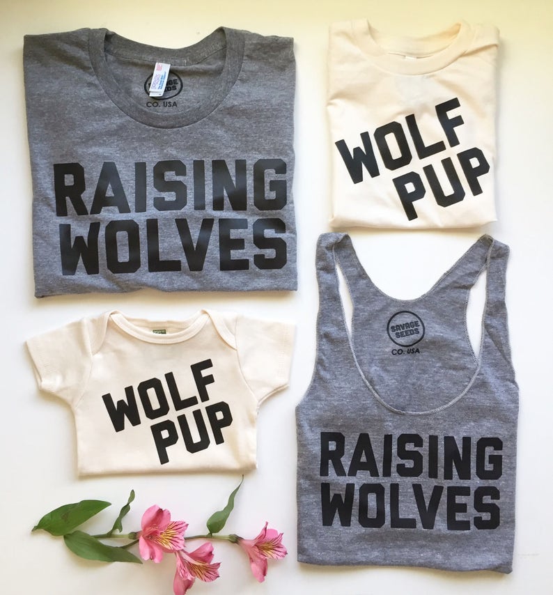 May include: A set of three shirts with the text "Raising Wolves" and "Wolf Pup" printed in black on a gray and cream background. The shirts are for adults and a baby.