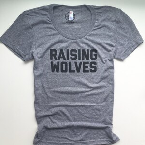 May include: A heather grey t-shirt with a black graphic that says "Raising Wolves".