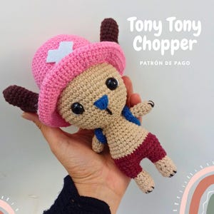 Puede incluir: Una muñeca de ganchillo hecha a mano de Tony Tony Chopper de la serie de anime One Piece. La muñeca tiene un sombrero rosa con una cruz blanca, un cuerpo beige y pantalones cortos burdeos. El texto "Tony Tony Chopper" y "PATRÓN DE PAGO" son visibles.