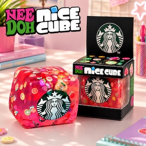 May include: A red cube-shaped product with colourful inclusions and a Starbucks logo. The product is in a black box with the Starbucks logo and the text "NEE DOH NICE CUBE". The cube is on a desk with other items.