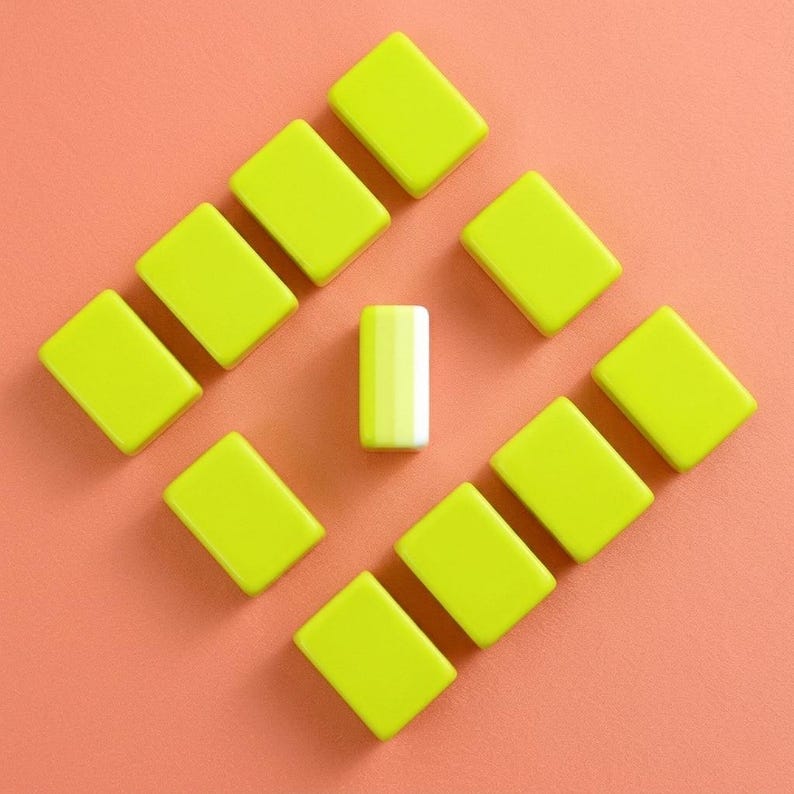 May include: A top-down view of a collection of small, rectangular, lime green objects arranged in a diamond shape on a peach-colored surface. One white and yellow striped rectangular object is in the center.