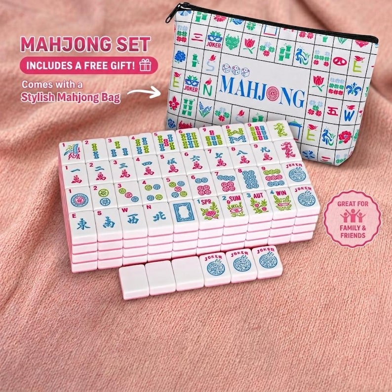 May include: A Mahjong set with white tiles featuring red, blue, and green symbols. The set includes a stylish zippered bag with a matching design. Text on the bag reads "MAHJONG". The set is presented on a pink surface.