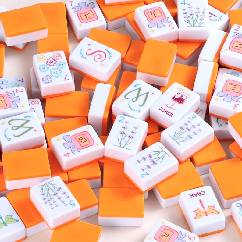 May include: A collection of orange and white Mahjong tiles. The tiles have various symbols, numbers, and illustrations, including flowers, characters, and suits. The tiles are scattered, creating a visually engaging pattern.