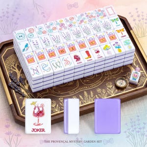 May include: A complete Mahjong set with white tiles featuring colorful illustrations of flowers, birds, and other designs. The set includes a wooden tray, a compass, and additional tiles. The text "THE PROVEN&Ccedil;AL MYSTERY GARDEN SET" is visible.