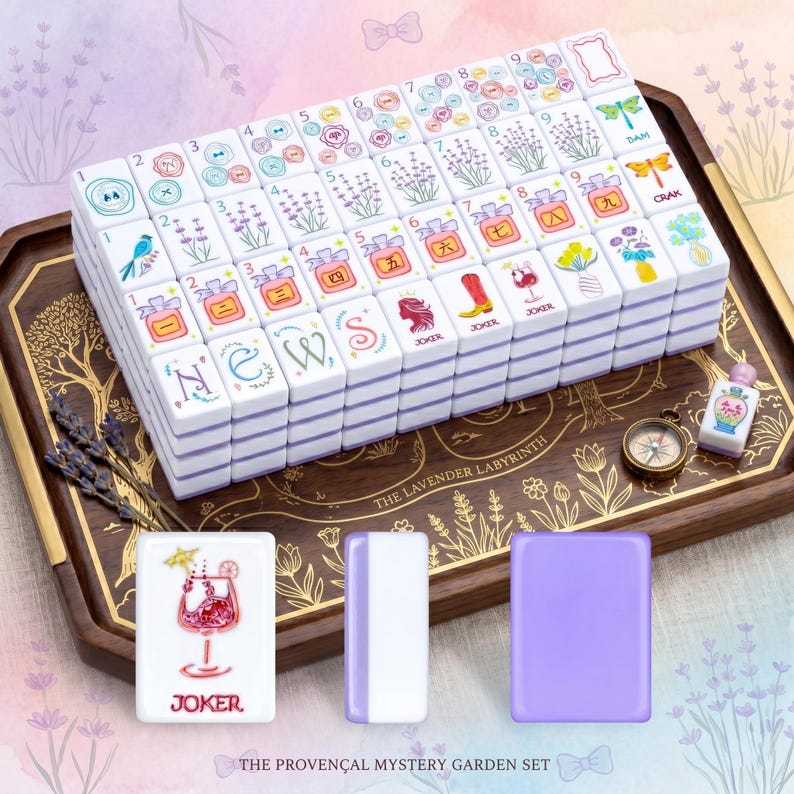 May include: A complete Mahjong set with white tiles featuring colorful illustrations of flowers, birds, and other designs. The set includes a wooden tray, a compass, and additional tiles. The text "THE PROVEN&Ccedil;AL MYSTERY GARDEN SET" is visible.