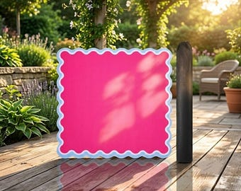 May include: A square, bright pink sign with a scalloped white and light blue border. The sign is positioned upright next to a tall, slender, black cylindrical pole. The surface of the sign is smooth and solid, reflecting soft sunlight and shadows.