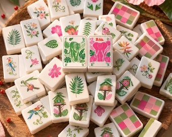 May include: A collection of white rectangular mahjong tiles featuring colorful illustrations of tropical plants, flowers, birds, treehouses, and geometric patterns. Two central tiles display a green tiger and a pink elephant respectively.