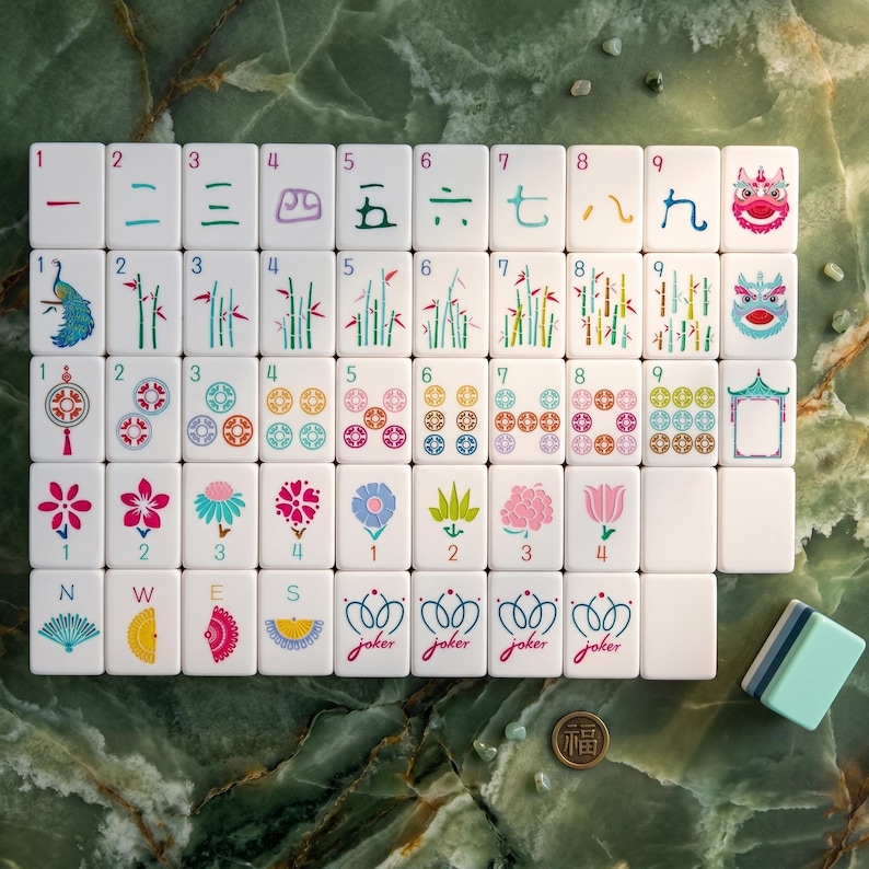 Może przedstawiać: Kompletny zestaw białych płytek do gry w Mahjong z r&oacute;żnymi symbolami i chińskimi znakami. Płytki przedstawiają smoki, kwiaty, bambus i liczby. Mały stos płytek i moneta są widoczne na zielonej marmurowej powierzchni.