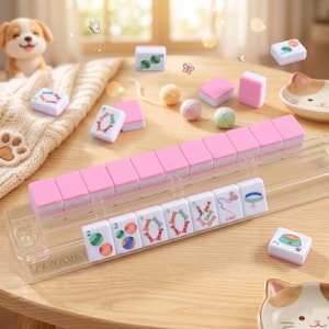 May include: A pink and white Pawjong set with a clear plastic tile holder. The tiles are white with colorful symbols and numbers. The set is on a light brown wooden table with a dog figurine and cat-shaped dish.