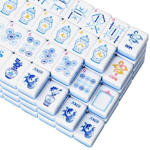 May include: A set of white rectangular mahjong tiles featuring blue and gold illustrations of vases, bamboo stalks, flowers, fish, and dragons. Several tiles are labeled with the text JOKER, BAM, or CRAK, alongside various numerical symbols.