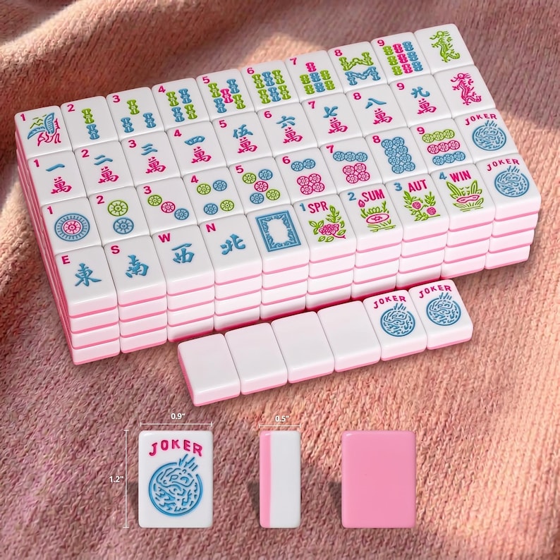 May include: A set of white and pink Mahjong tiles with various symbols and characters. The tiles are stacked and arranged, with some individual tiles showing measurements of 1.2" x 0.9" x 0.5". The word "JOKER" is visible on some tiles.