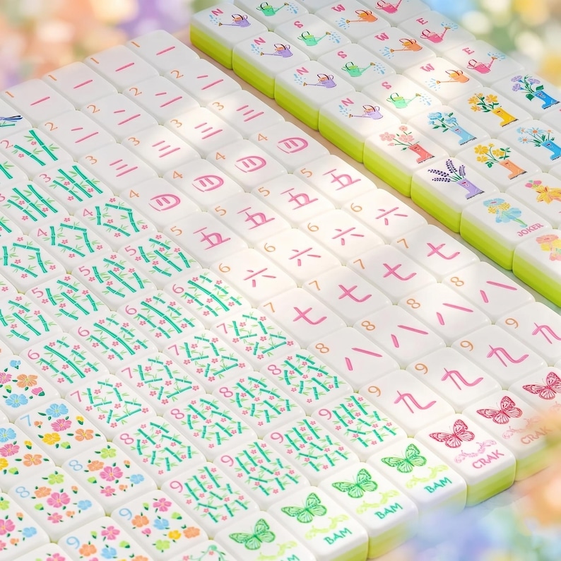 May include: A set of white Mahjong tiles with various symbols, numbers, and illustrations. The tiles feature bamboo, flowers, butterflies, and Chinese characters. The edges are green, and the tiles are arranged in neat rows.