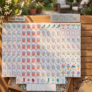 May include: A 160-piece Mahjong set with white tiles featuring various symbols and numbers. The set includes dots, bams, cracks, dragons, winds, flowers, jokers, and spare tiles. The set is displayed on a wooden surface.