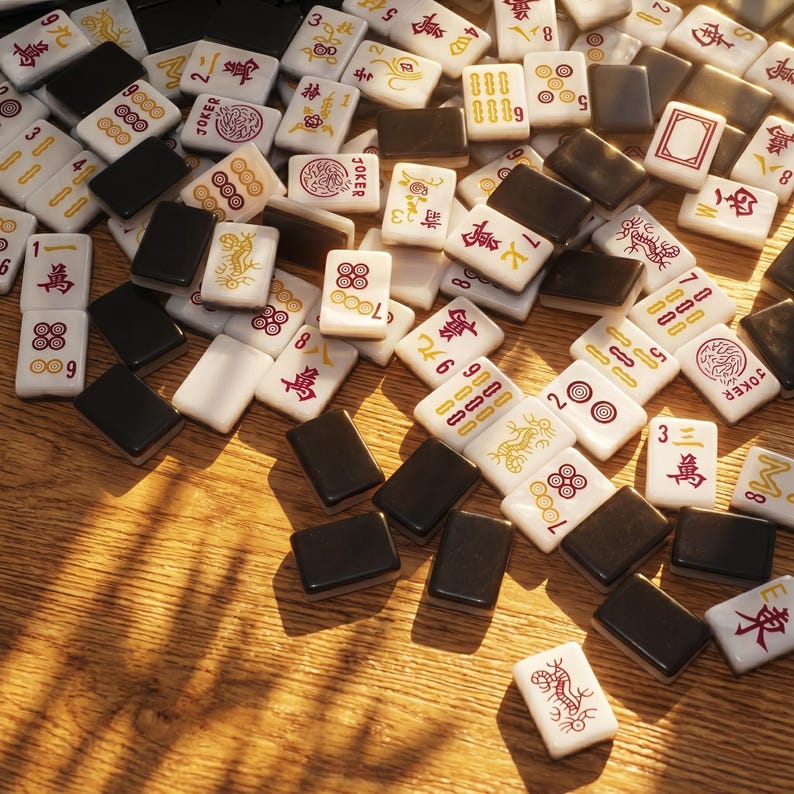 Puede incluir: Una colecci&oacute;n de fichas de Mahjong de color marfil con detalles en blanco y negro dispersas sobre una superficie de madera. Las fichas presentan varios s&iacute;mbolos, n&uacute;meros y caracteres chinos en rojo y dorado. Algunas fichas son negras.