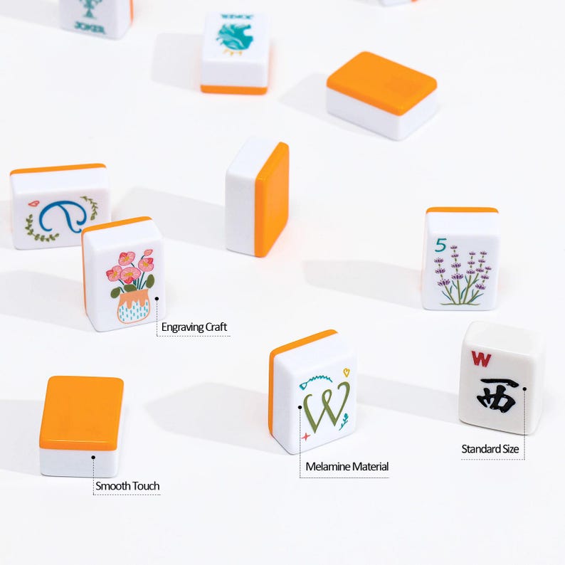 May include: A collection of white and orange Mahjong tiles. Each tile features unique designs, including floral patterns, symbols, and the letter "W". The tiles are labeled "Engraving Craft", "Smooth Touch", "Melamine Material", and "Standard Size".