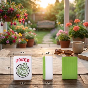 May include: Three rectangular game pieces are displayed on a wooden table. One piece has the word "JOKER" in red and a green maze design. The other two pieces are white with green accents and green with vertical lines. The pieces measure 0.9" x 1.2" and 0.5" x 0.9".