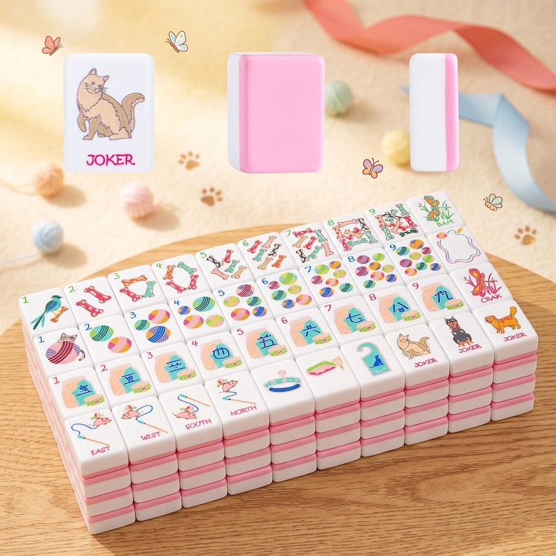 May include: A set of white and pink Mahjong tiles with colorful illustrations and Chinese characters. The tiles feature images of cats, dogs, and other symbols. Some tiles have the word "JOKER" printed on them. The tiles are stacked on a wooden surface.
