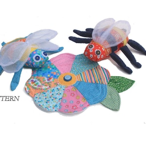 Peut inclure: Jouets d'insectes en tissu faits à la main et un coussin en forme de fleur. Les insectes ont des corps à motifs, des ailes transparentes et des pattes sombres. Le coussin de fleur est fait de pièces de tissu colorées avec un bouton au centre. Le mot "PATTERN" est visible.