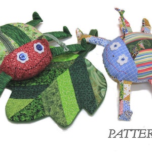 Peut inclure: Deux jouets en tissu faits main en patchwork en forme d'insectes. L'un est une coccinelle verte et rouge avec de grands yeux bleus. L'autre est un insecte bleu et multicolore avec des yeux blancs. Le mot "PATTERN" est imprimé sous les jouets.