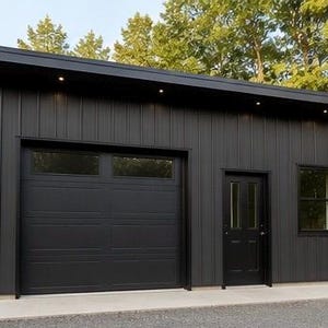 May include: A detached garage building with matte black vertical metal siding, a single-car garage door with rectangular windows, a matching black entry door with two vertical glass panels, and a single window, all set under a flat roof.