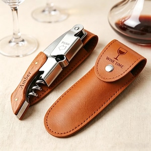 May include: A stainless steel corkscrew with a wooden handle engraved with the name Amber and a PUSH arrow indicator. It is accompanied by a tan faux leather carrying case featuring a snap button closure and the text WINE TIME with a wine glass icon.