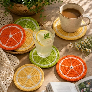 May include: A collection of round, crocheted coasters designed to resemble citrus fruit slices. The set includes orange, lemon, and lime patterns featuring vibrant orange, yellow, and green yarn with white accents representing the fruit segments.