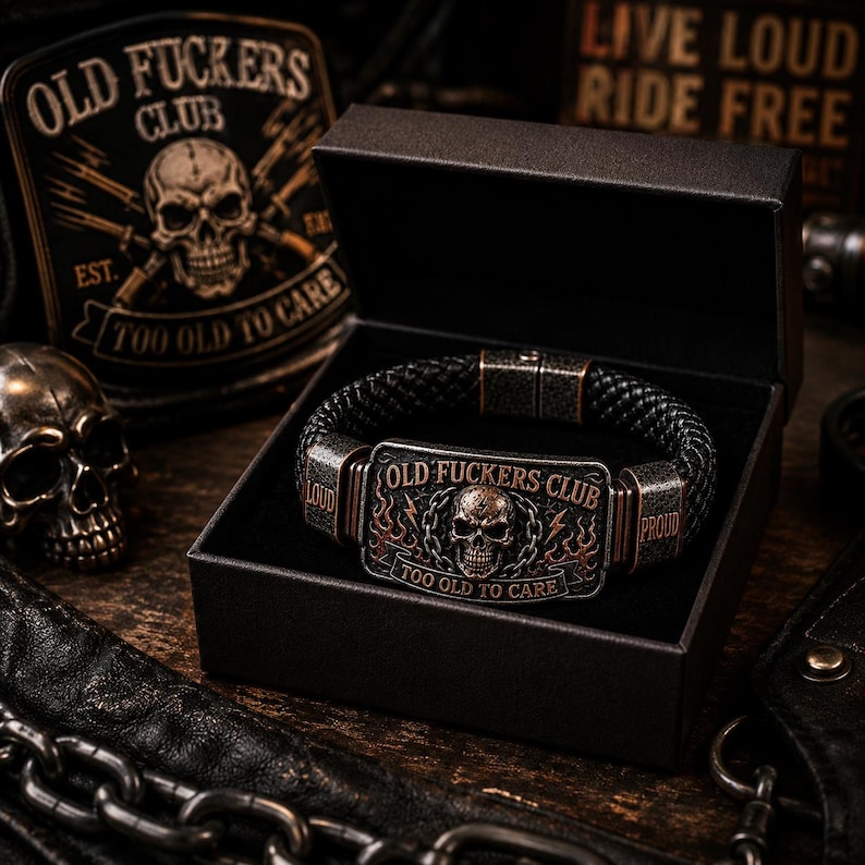 May include: A black braided leather bracelet featuring a rectangular metal plate with a skull graphic, flames, and the text OLD FUCKERS CLUB and TOO OLD TO CARE. The bracelet has metal side accents labeled LOUD and PROUD, presented in a black box.