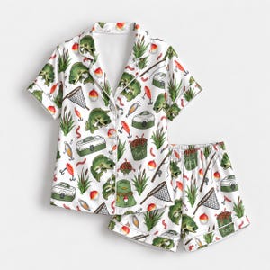 May include: A white short-sleeved button-down pyjama shirt and matching shorts set featuring a repeating pattern of green fish, fishing tackle boxes, red and white floats, fishing nets, rods, and buckets labelled with the word BAIT in green.