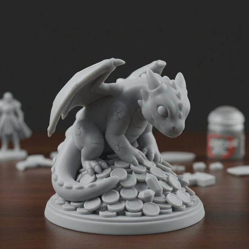 May include: A grey dragon figurine with outstretched wings, sitting on a pile of coins. The dragon has detailed scales and a curious expression. The figurine is likely for tabletop gaming or fantasy decor.