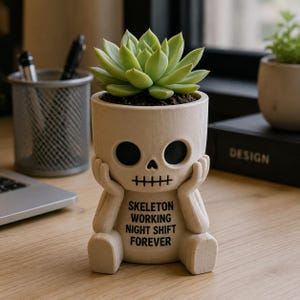May include: A beige skull-shaped planter featuring a seated skeleton figure with hands resting on its cheeks. The front displays the black text SKELETON WORKING NIGHT SHIFT FOREVER. A green succulent plant is potted inside the top of the skull.