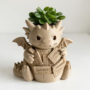 May include: A beige 3D-printed dragon planter featuring a small green succulent plant. The dragon figure has wings, horns, and a tail, and it is holding a collection of rectangular tiles, each clearly embossed with the text EXPIRED COUPON.
