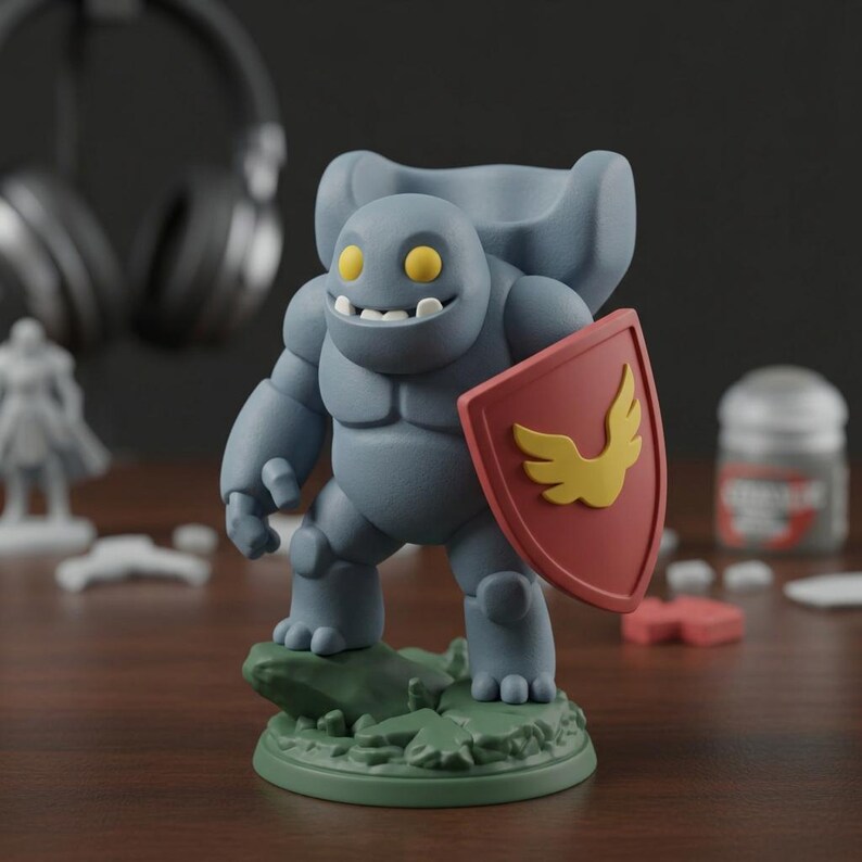 May include: A gray figurine of a smiling, muscular creature with yellow eyes and a shield featuring a yellow wing design. The figurine stands on a green base with a rock-like texture. The shield is red.