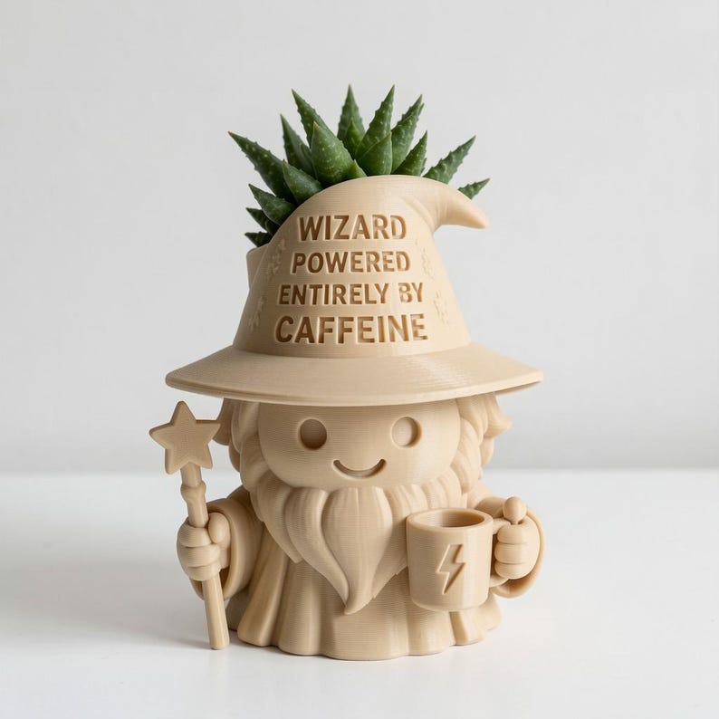 May include: A beige 3D-printed planter shaped like a wizard with a beard, holding a star-topped wand and a mug with a lightning bolt icon. The wizard hat features the text WIZARD POWERED ENTIRELY BY CAFFEINE. A green succulent plant sits inside the hat.