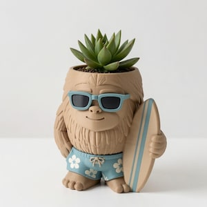 May include: A tan-colored planter shaped like a furry creature wearing light blue sunglasses and blue swim trunks with a white floral pattern. The creature holds a light blue surfboard under one arm, and a green succulent plant sits inside.