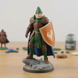 May include: A miniature fantasy figure of a knight, wearing brown and green armor, a blue cape, and a green hat. The figure holds a shield with a fox emblem. The figure stands on a rocky base. A miniature figure is in the background.