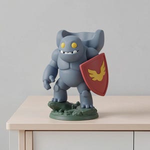 May include: A gray figurine of a cartoon-like character with yellow eyes and a wide grin, holding a red shield with a yellow emblem. The figure stands on a green base, and is posed as if ready for battle.