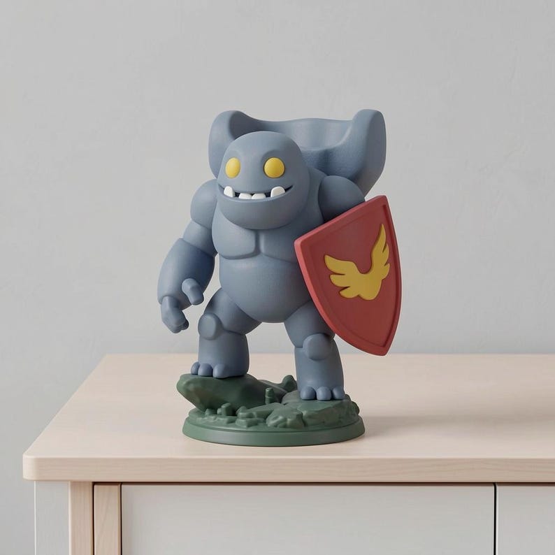 May include: A gray figurine of a cartoon-like character with yellow eyes and a wide grin, holding a red shield with a yellow emblem. The figure stands on a green base, and is posed as if ready for battle.