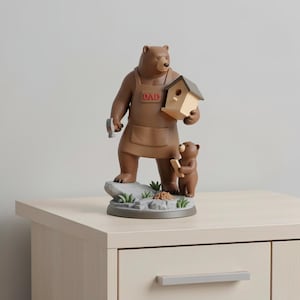 K&ouml;nnte beinhalten: Eine braune B&auml;renfigur mit Hammer und Vogelhaus. Der B&auml;r tr&auml;gt eine braune Sch&uuml;rze mit dem Wort "DAD" und steht mit einem kleineren B&auml;ren, der ein Holzbrett h&auml;lt. Die Figur steht auf einem grauen Sockel mit gr&uuml;nem Gras und kleinen Steinen.
