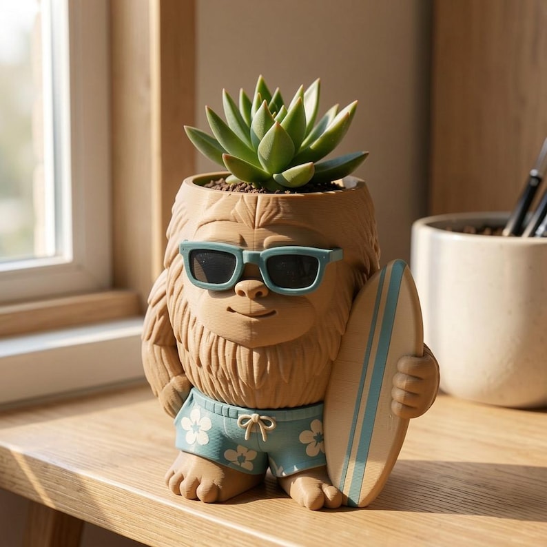 May include: A tan, textured planter shaped like a furry creature wearing light blue sunglasses and blue swim trunks with a white floral pattern. The creature holds a light blue and tan surfboard, and a green succulent plant grows from its head.