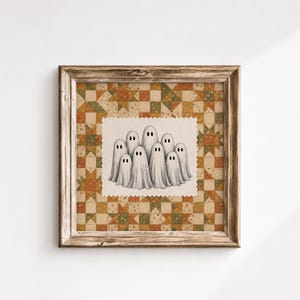 May include: A framed square artwork featuring a central off-white fabric patch with a scalloped edge, displaying a charcoal pencil illustration of nine ghosts. The background is a patchwork quilt pattern in shades of orange, green, and tan.