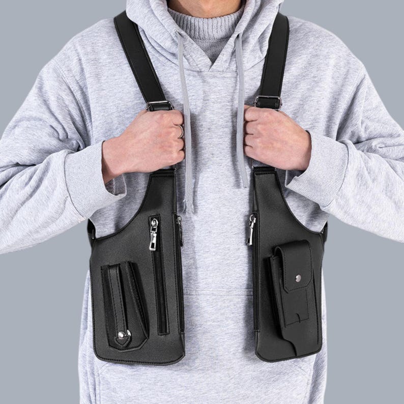 Premium black leather shoulder holster bag and techwear chest rig with an adjustable X-strap design. Includes a vertical zipper pocket and a utility pouch with a silver snap button, shown isolated on a solid gray background.