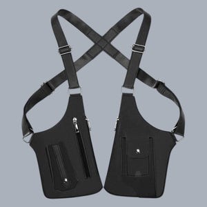 Premium black leather shoulder holster bag and techwear chest rig with an adjustable X-strap design. Includes a vertical zipper pocket and a utility pouch with a silver snap button, shown isolated on a solid gray background.
