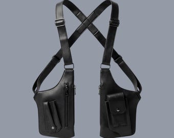 May include: A black dual-holster shoulder bag featuring adjustable straps that cross at the back. The bag includes two main compartments with vertical zippers, one front pocket with a snap-button flap, and a secondary pocket with a vertical strap.