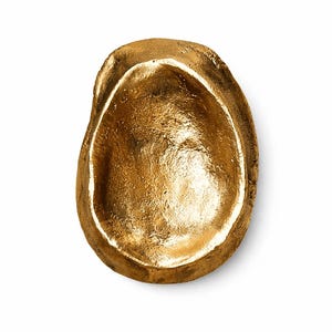 Könnte beinhalten: Eine kleine, ovale Dekoschale mit metallisch goldener Oberfläche. Die Textur ist uneben und organisch gestaltet, mit einer tiefen, konkaven Mitte und dicken, unregelmäßigen Rändern, was an ein gegossenes Metallobjekt oder eine Steinform erinnert.