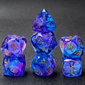 May include: A set of seven polyhedral dice made of translucent blue and purple resin with a faceted, crystalline texture. Each die features engraved numbers filled with gold-colored ink, including a d20, d12, d10, d8, d6, d4, and a percentile die.