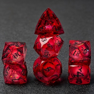 Può includere: Un set di sette dadi poliedrici rosso traslucido con numeri neri. I dadi sono disposti in tre pile, presentando varie forme geometriche tra cui un tetraedro, un ottaedro, un dodecaedro e un icosaedro, tutti con bordi affilati.
