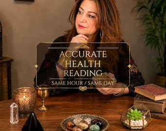 May include: A wooden table featuring a gold-toned bowl filled with assorted polished gemstones, a black pyramid, a clear crystal point, a gold chalice, a lit candle in a patterned holder, and a glass terrarium containing a small green succulent.