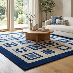 May include: A rectangular area rug featuring a geometric pattern of nested squares in varying shades of blue and cream. The rug has a solid dark blue border and a cream-colored field with repeating square motifs in light, medium, and dark blue tones.