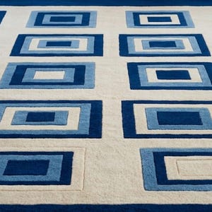 May include: A rectangular area rug featuring a repeating pattern of nested rectangles in shades of dark blue, light blue, and white. The design consists of multiple concentric rectangular frames arranged in a grid across a cream-colored background.